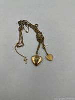 All three tangled gold-tone necklaces with heart lockets and cross pendant visible