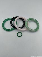Four jade bangles and green jade ring displayed on white background