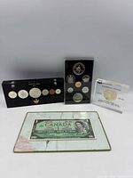 All coin sets and framed banknote displayed together