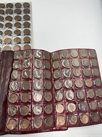 Open red Slip E-Z folder showing multiple rows of Canadian pennies in clear pockets; part of binder page with coins visible