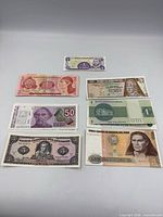 Seven banknotes laid out for full front view