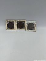 Three of fourteen pennies in holders showing dates and provincial identification