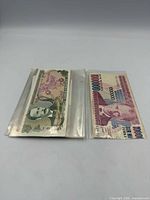Two banknotes in plastic sleeves; 100,000 Turkish Lira note visible