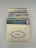 Stack of annual Royal Canadian Mint coin set folders, years hand-marked 1971-1991
