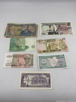 Seven different banknotes laid out including Kenya, Mozambique, Burundi, Zambia, Lebanon, Burundi 50-F, Sudan