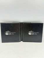 Two black binders with First Commemorative Mint Inc. logo
