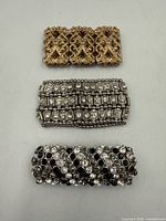 Front view of three stretch bracelets showing gold-tone filigree, silver-tone rectangular rhinestones, silver-tone round rhinestones with black accents