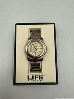 Watch in box front view showing dial and bracelet