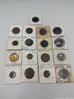 Front view of 17 assorted world coins in flips showing obverse sides with handwritten labels