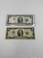 Front view of both $2 notes, top note sleeved