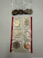 Full view of loose nickels in plastic bag above sealed Denver Mint coin set