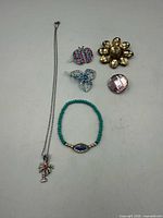 All six jewellery items laid out: necklace, bracelet, two brooches, two pins