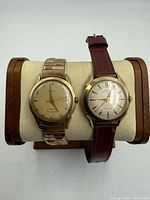 Front view of both Elgin watches on display stand