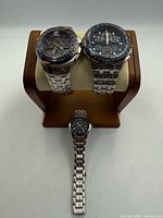 Front view of two large chronograph watches and one smaller dress watch on stand