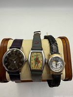 Front view of three wristwatches on display stand