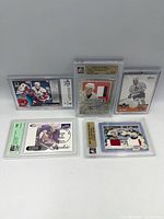Five memorabilia cards in holders, including dual jersey, autograph patch, and graded rookie