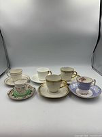 Front view of six teacups with saucers showing varied patterns