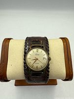 Front view of Tradition De Luxe wristwatch on display stand showing dial and leather cuff band