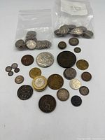 Full lot view showing two bags of small silver-tone coins and assorted loose coins