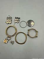 All watch parts laid out: gold-tone cases, stainless steel case back, bracelet links