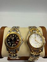 Front view of both TAG Heuer watches on stand showing dials and bezels