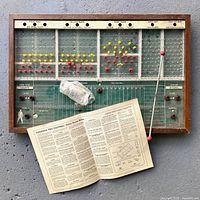 Full view of game board with pegs, shooter rod, instructions sheet and bag of pieces