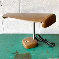 Front side view of brown fluorescent desk lamp on green table