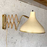 Side view of brass scissor arm lamp extended on wall