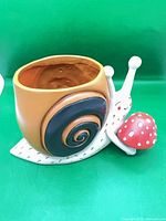 Front view of snail planter showing opening and mushroom accent