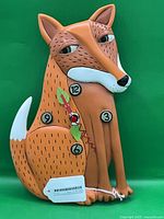 Front view of stylized fox clock showing numerals and pendulum detail