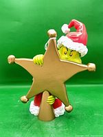 Front view of Grinch tree topper showing character and gold star