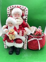Front view showing Santa, child, teddy bear, wrapped gift, gingerbread chair and sack of gifts