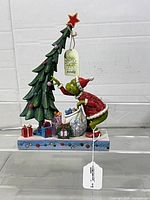 Full front view of Jim Shore Grinch figurine with tree, presents and tags visible
