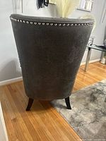 Rear view of gray armchair showing nailhead trim and tapered legs