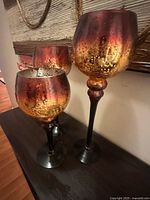 Three stemmed metallic glass vases on table
