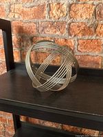 Front angled view of silver-tone metal wire orb on shelf