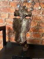 Front view of abstract face with finger to lips on base