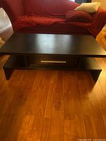 Top and front view of dark brown coffee table showing drawer and shelf