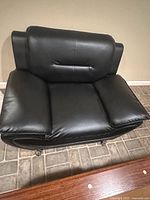 Front view of black leather lounge chair showing seat, backrest, arm cushions