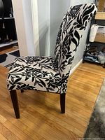 Profile view of upholstered side chair showing high back, floral fabric, wooden legs