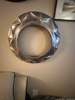 Front view of circular silver-toned faceted wall decor ring