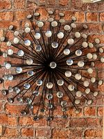 Full view of black metal sunburst wall art on brick background