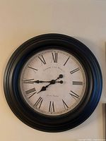 Front view of black round clock showing face details