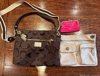 Overview of three bags: brown Coach shoulder bag, pink Roots coin purse, cream Coach satchel