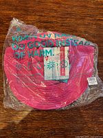 Sealed Coolibar bright pink sun hat in plastic bag