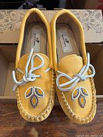 Top view of yellow moccasins showing beadwork, laces and interior branding