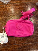 Front view of bright pink Lululemon Team Canada belt bag with tags attached, crest and CAN patch visible