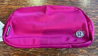Front view of bright pink Lululemon belt bag showing logo patch and fabric