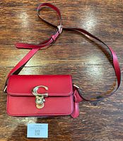 Full view of red Coach purse with strap and authentication card