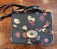Front view of Coach floral crossbody purse showing flap and turnlock